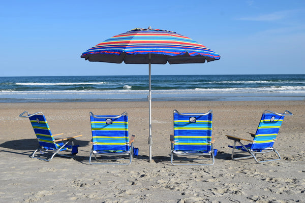 A set of four foldable beach chairs with blue and yellow stripes, arranged on a beach with a striped beach umbrella. 