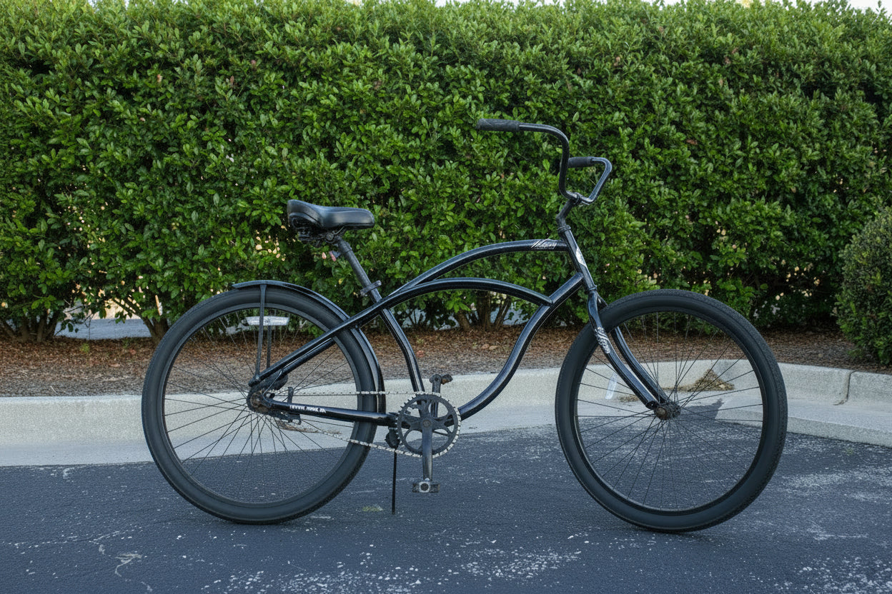 Black bicycle parked on a sidewalk with trees and a building in the background